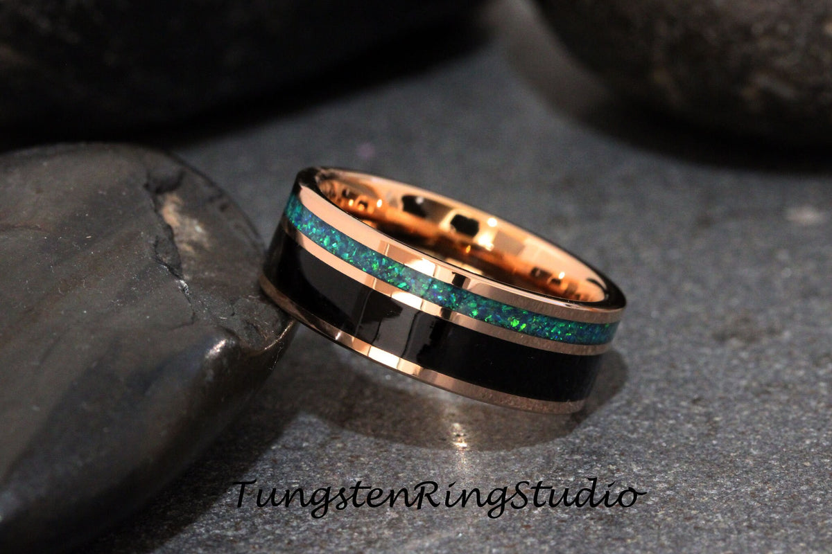 May include: A black tungsten ring with a rose gold band and two green opal inlay stripes. TungstenRingsStudio is printed on the background.