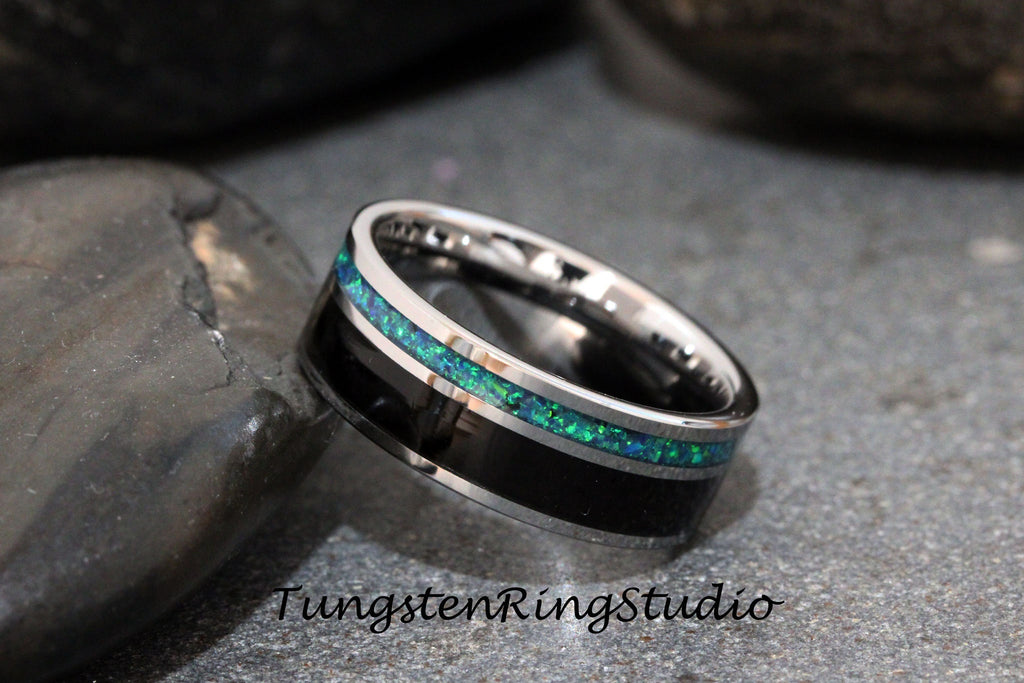 May include: A silver tungsten ring with a black inlay and a green opal inlay. The ring is on a gray background.