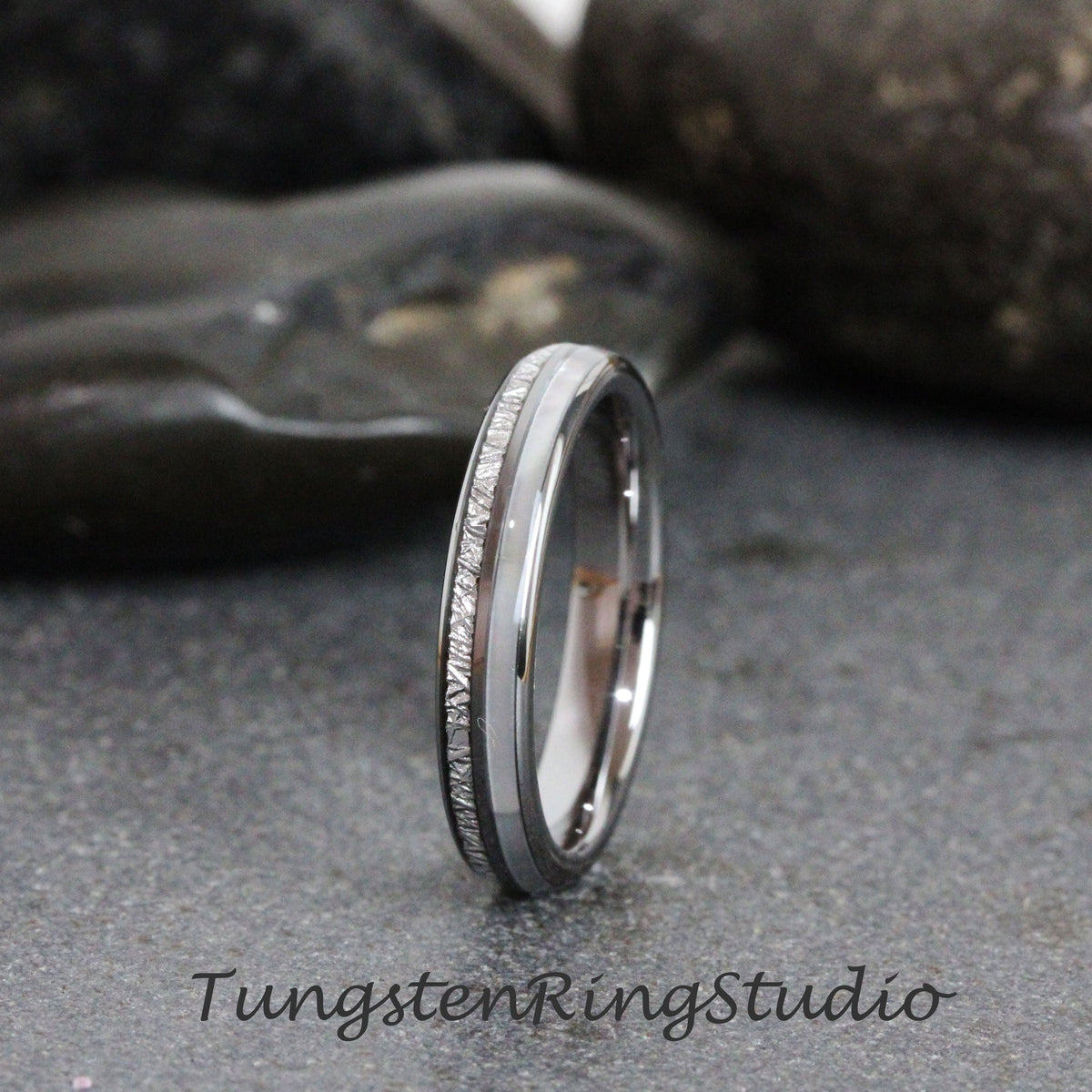 May include: A silver tungsten carbide ring with a white inlay and a textured band. Tungsten Ring Studio.