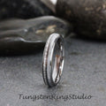 May include: A silver tungsten carbide ring with a white inlay and a textured band. Tungsten Ring Studio.