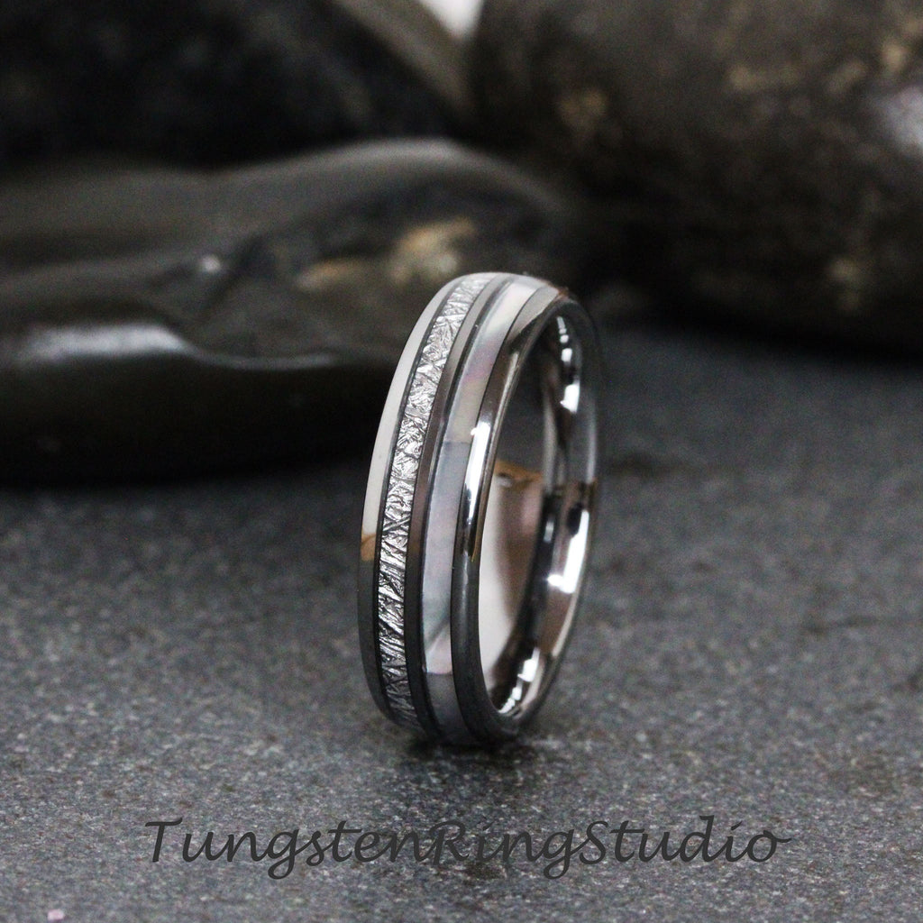 May include: A silver tungsten carbide ring with a white and gray inlay. The ring has a brushed finish and a beveled edge.