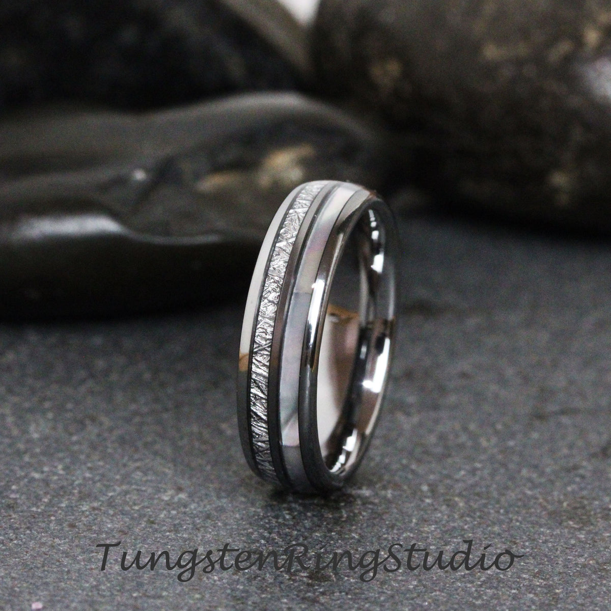 May include: A silver tungsten carbide ring with a white and gray inlay. The ring has a brushed finish and a beveled edge.