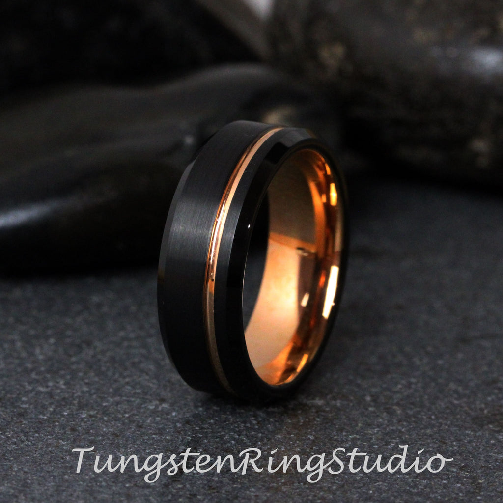 May include: A black tungsten ring with a rose gold inlay. The ring has a brushed finish and a beveled edge.