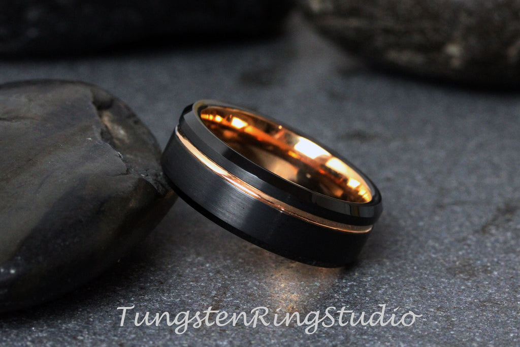 May include: A black tungsten ring with a rose gold inlay. The ring has a beveled edge and a brushed finish.