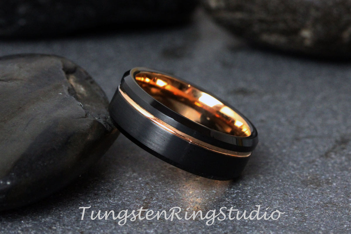 May include: A black tungsten ring with a rose gold inlay. The ring has a beveled edge and a brushed finish.