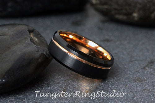 May include: A black tungsten ring with a rose gold inlay. The ring has a beveled edge and a brushed finish.