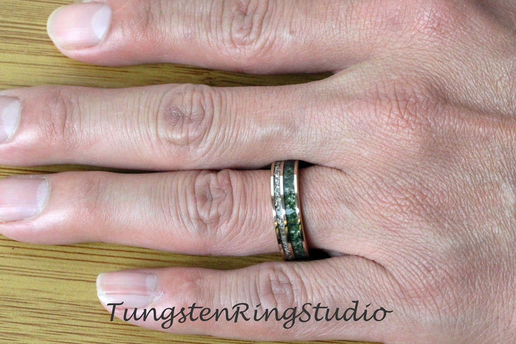 May include: A rose gold ring with a band of green stone and a band of white stones. The ring is on a person's finger. The text "TungstenRingStudio" is visible in the image.
