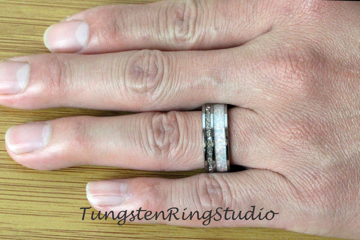 May include: A silver tungsten ring with a white opal inlay. The ring is on a person's finger.