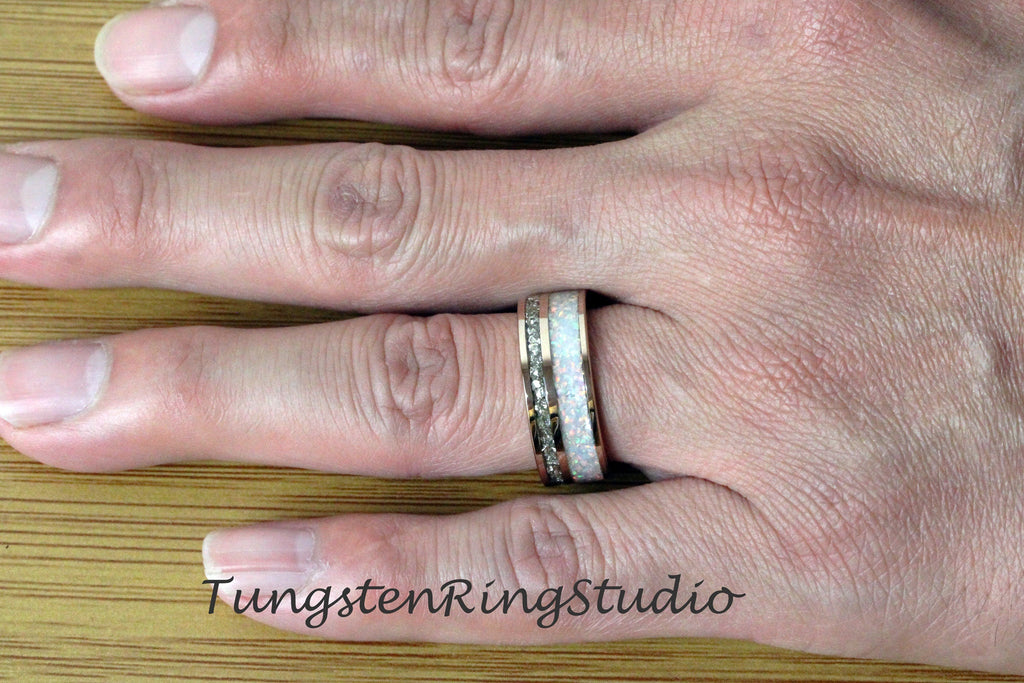 May include: A silver tungsten carbide ring with a white opal inlay. The ring is on a person's finger.