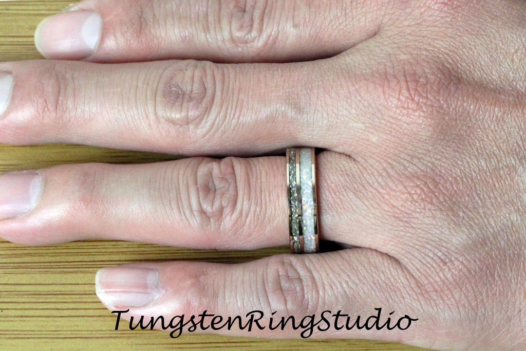 May include: A close-up of a tungsten ring with a white and rose gold inlay. The ring is on a person's finger.
