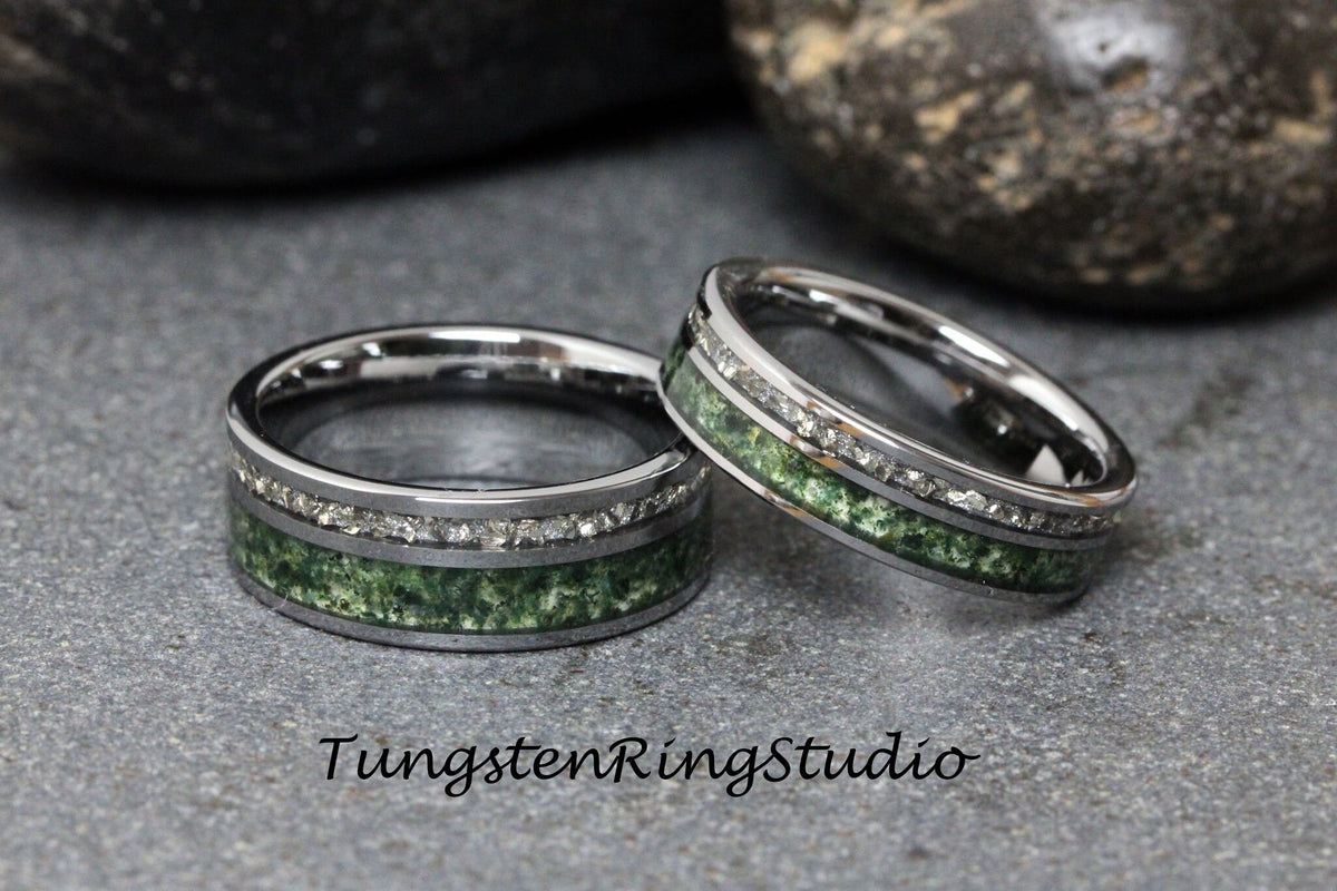 May include: Two silver tungsten carbide rings with a green and silver inlay. The rings have a row of small diamonds around the inlay.