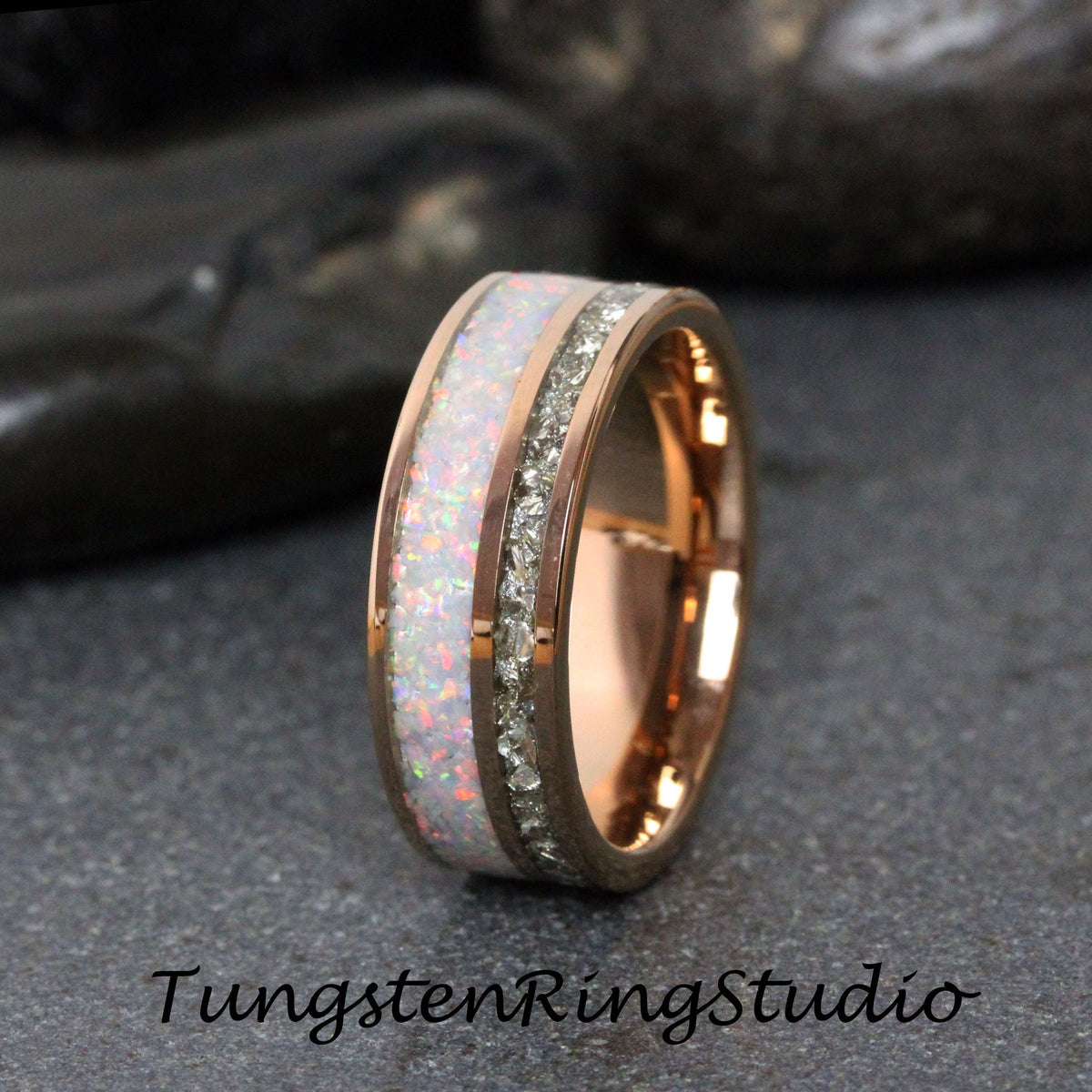 May include: A rose gold tungsten carbide ring with a white opal inlay and a row of clear cubic zirconia stones.
