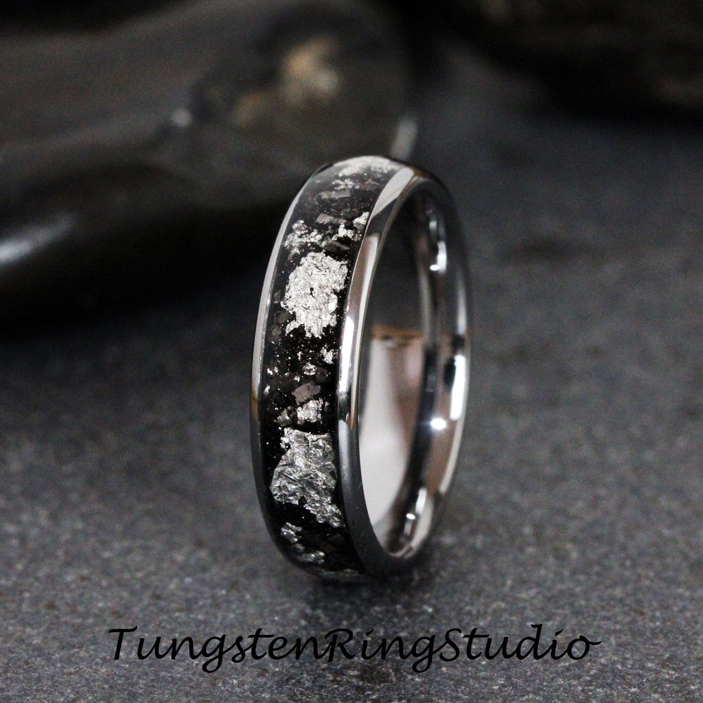 May include: A silver and black tungsten carbide ring with a silver inlay design. The ring is polished and has a beveled edge.