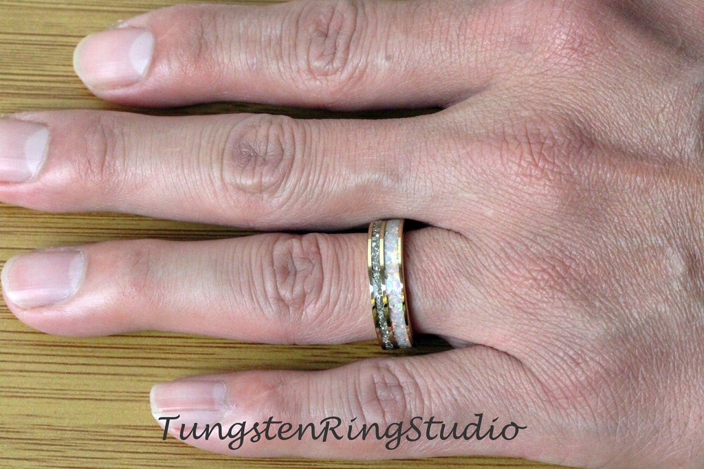 May include: A close-up of a tungsten ring with a white and gold inlay. The ring is on a person's finger.