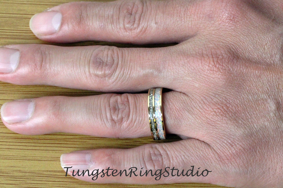 May include: A close-up of a tungsten ring with a white and gold inlay. The ring is on a person's finger.