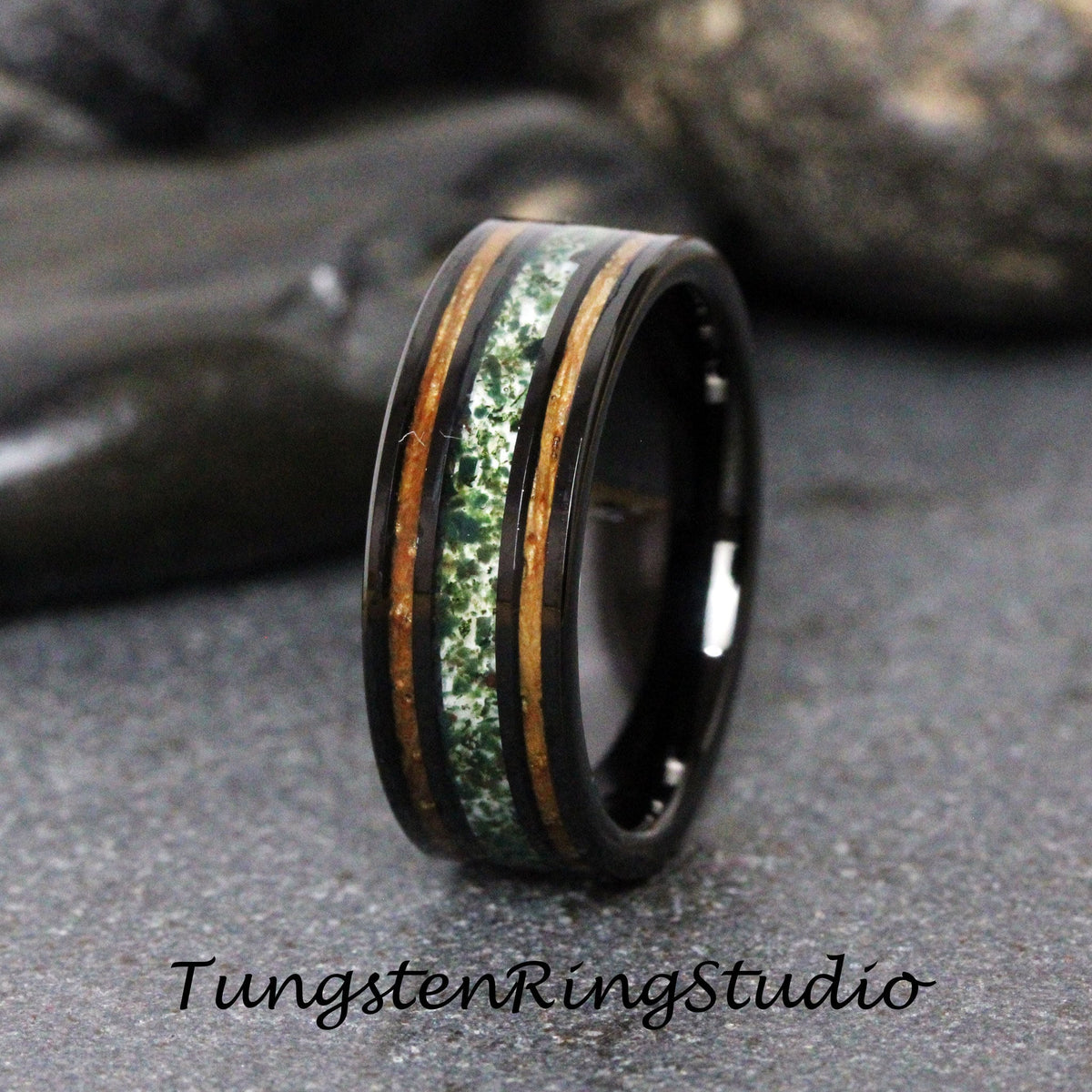 May include: Black tungsten ring with a green and brown inlay. The ring has a polished finish and a beveled edge.