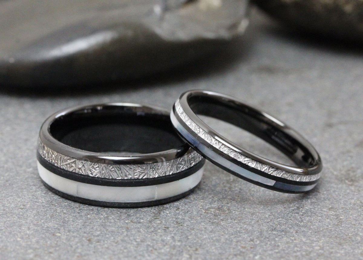 May include: Two black wedding bands with a silver inlay and white mother of pearl accents.