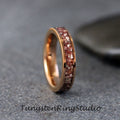May include: A rose gold tungsten carbide ring with a band of embedded red and white stones.