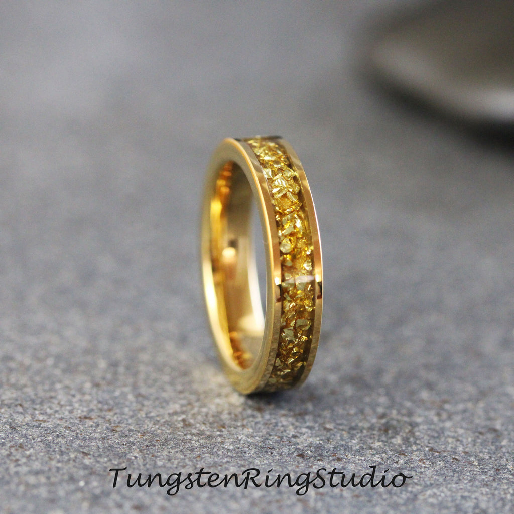May include: A gold tungsten carbide ring with a band of yellow gold-colored particles.