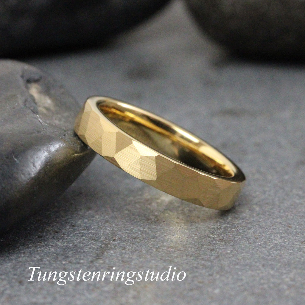 May include: A gold tungsten carbide ring with a hammered finish. The ring is a simple band with a slightly rounded edge.