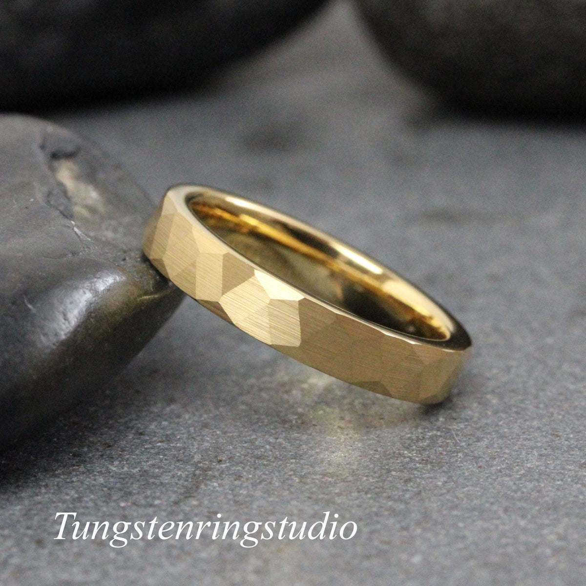 May include: A gold tungsten carbide ring with a hammered finish. The ring is a simple band with a slightly rounded edge.