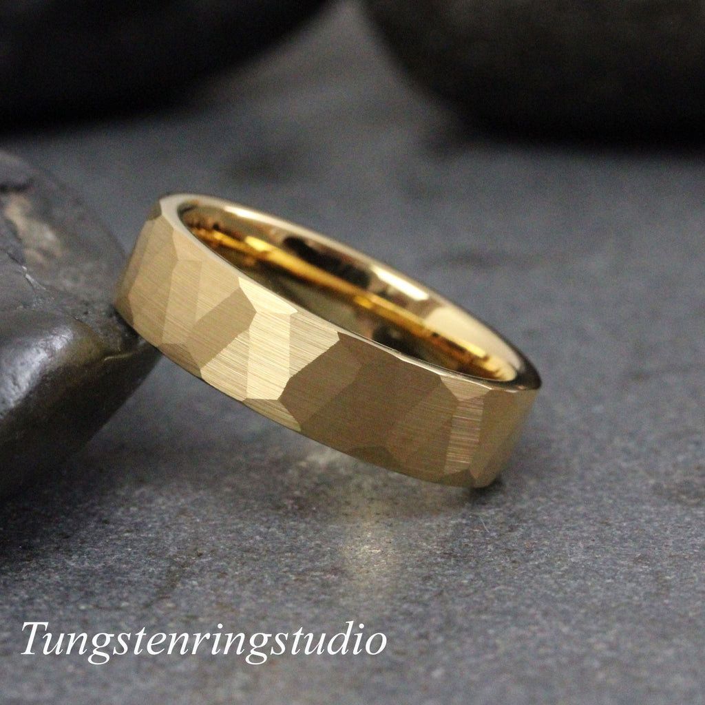 May include: A gold tungsten carbide ring with a hammered finish. The ring is thick and has a rounded edge.