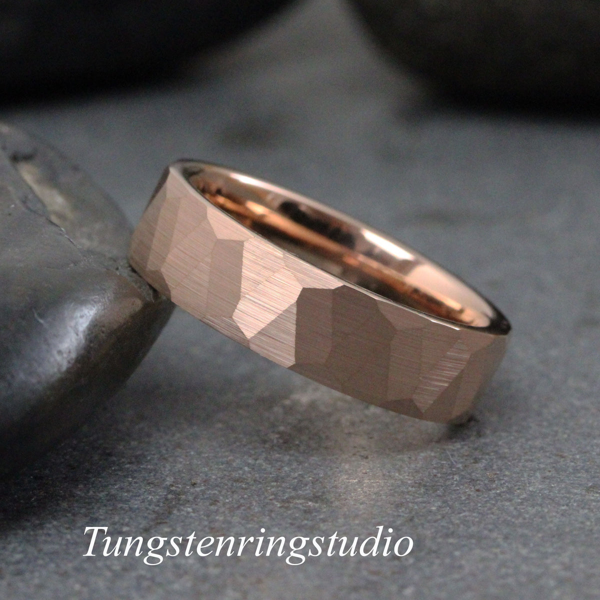 May include: Rose gold tungsten carbide ring with a hammered finish. The ring is a simple band with a slightly rounded edge.
