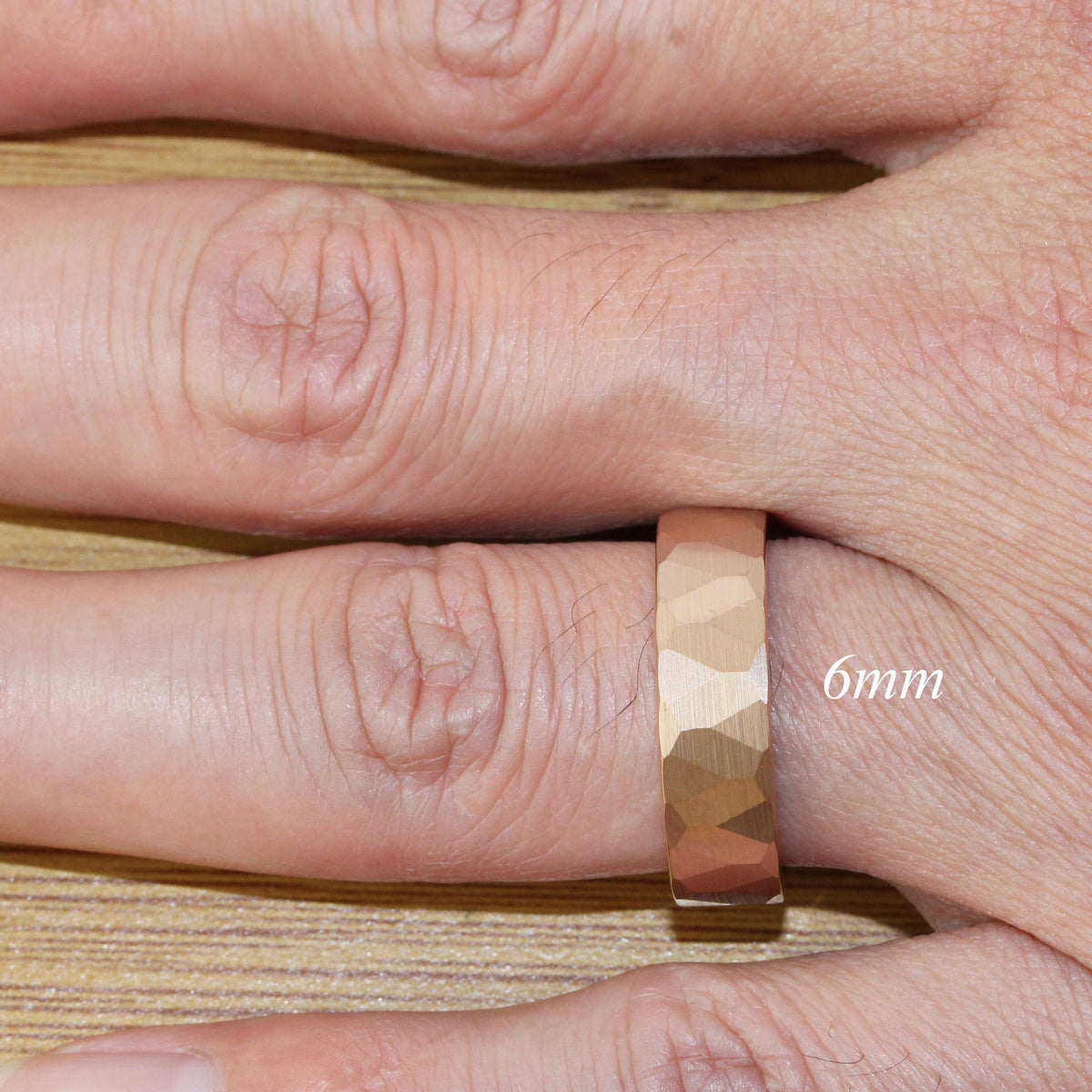 May include: A gold-toned hammered metal ring with a 6mm width. The ring is shown on a finger.