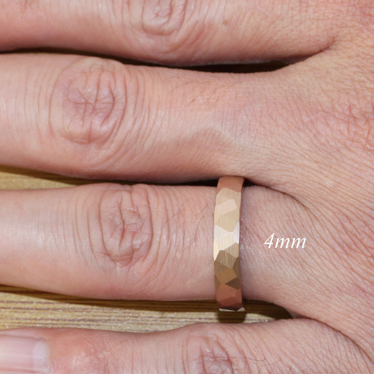 May include: A gold-toned ring with a textured, faceted design. The ring is 4mm wide and is worn on a finger.
