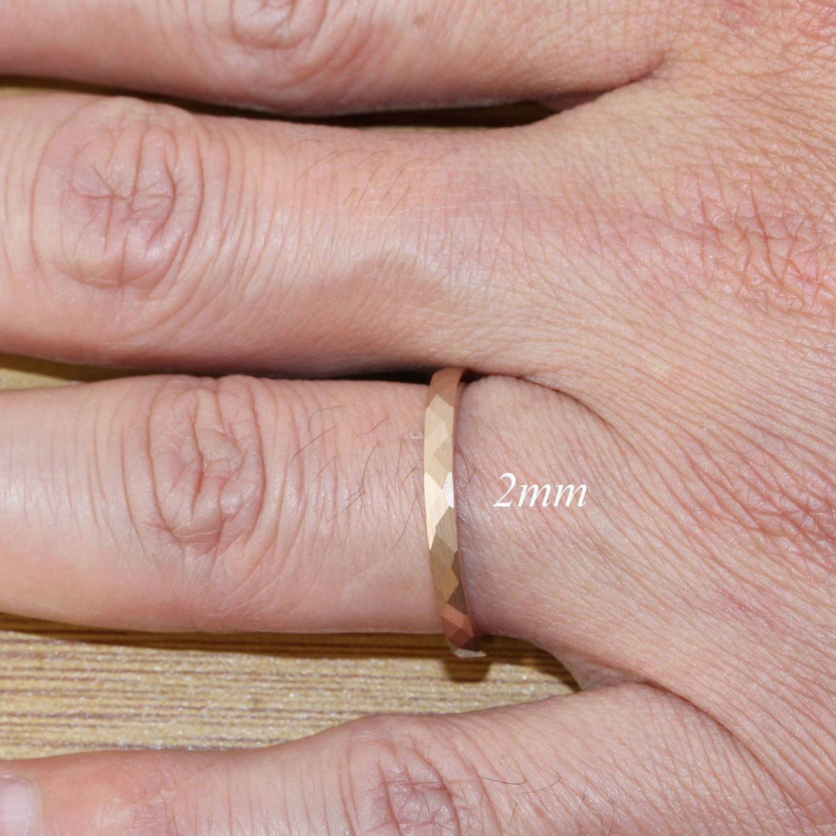 May include: A gold-toned ring with a faceted design. The ring is 2mm wide.