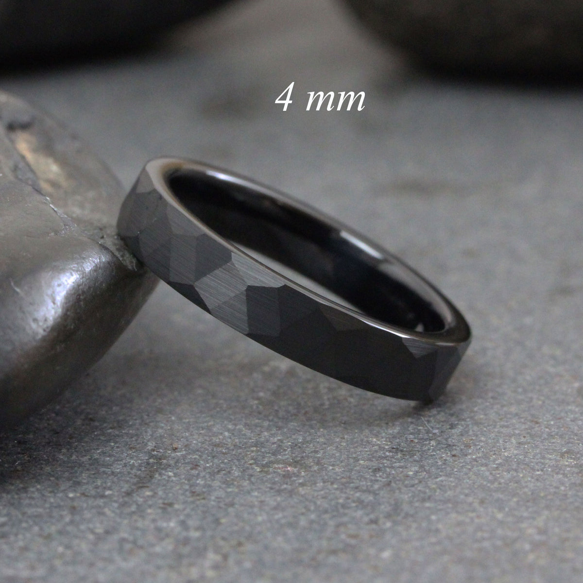 May include: A black tungsten carbide ring with a hammered finish. The ring is 4 mm wide.