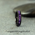 May include: A black tungsten ring with a band of purple glitter. Tungsten Rings Studio.