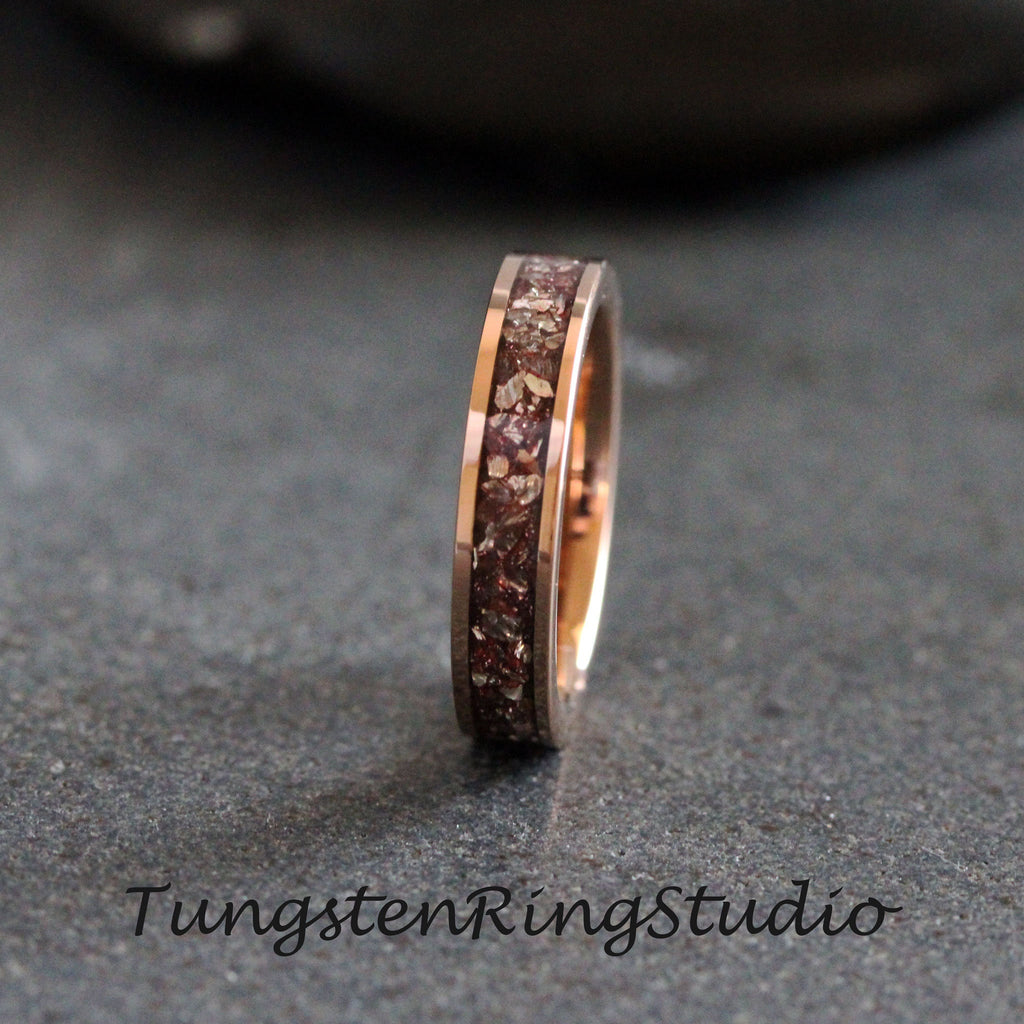 May include: A rose gold tungsten carbide ring with a band of embedded brown and silver glitter.