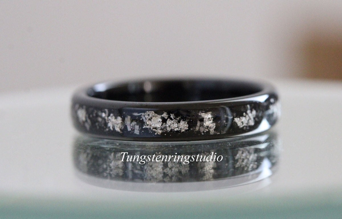 May include: A black tungsten ring with a silver inlay design. The ring is polished and has a smooth finish.