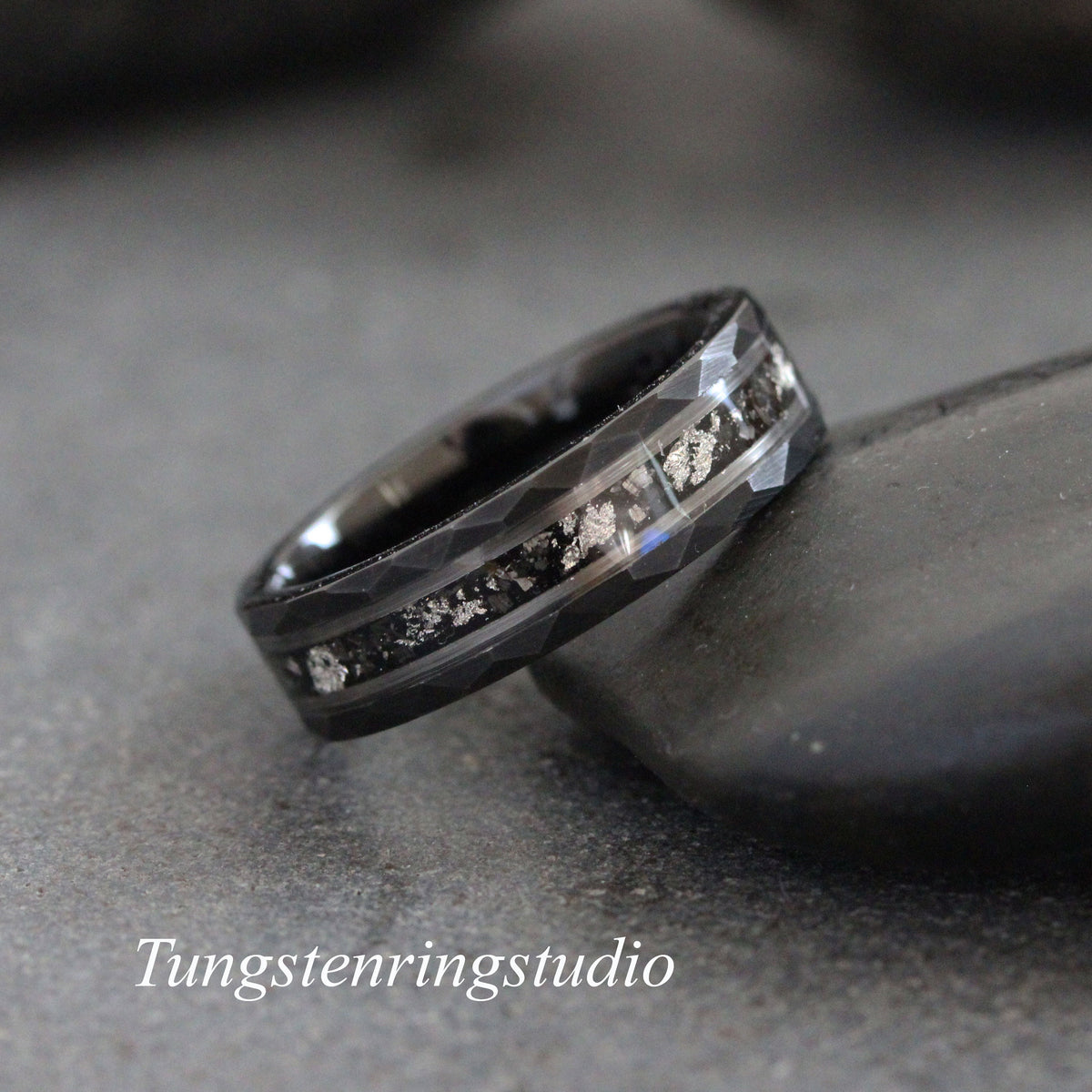 May include: A black tungsten carbide ring with a silver inlay. The ring has a beveled edge and a brushed finish.