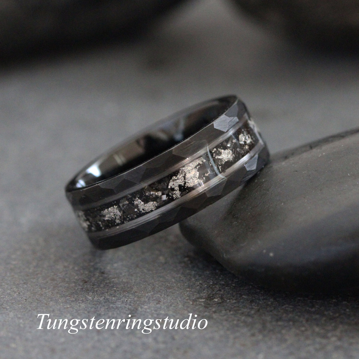 May include: Black tungsten carbide ring with a hammered finish and a silver inlay. The inlay has a speckled pattern.