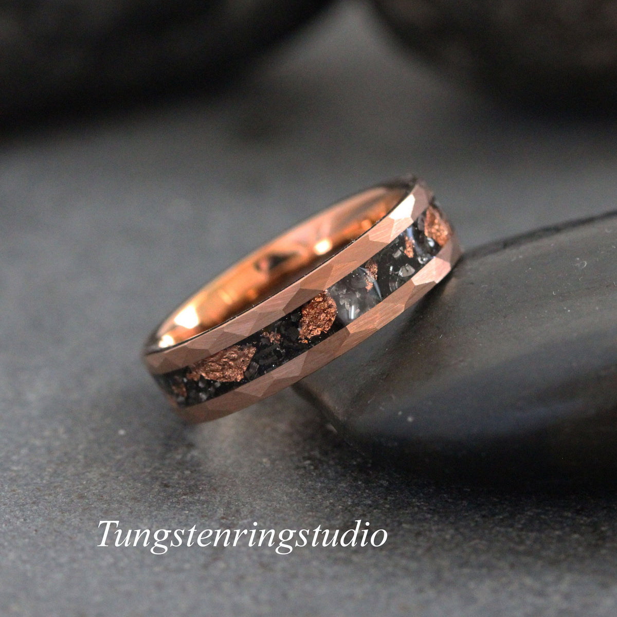 May include: A rose gold tungsten carbide ring with a black and copper inlay. The ring has a beveled edge and a polished finish.