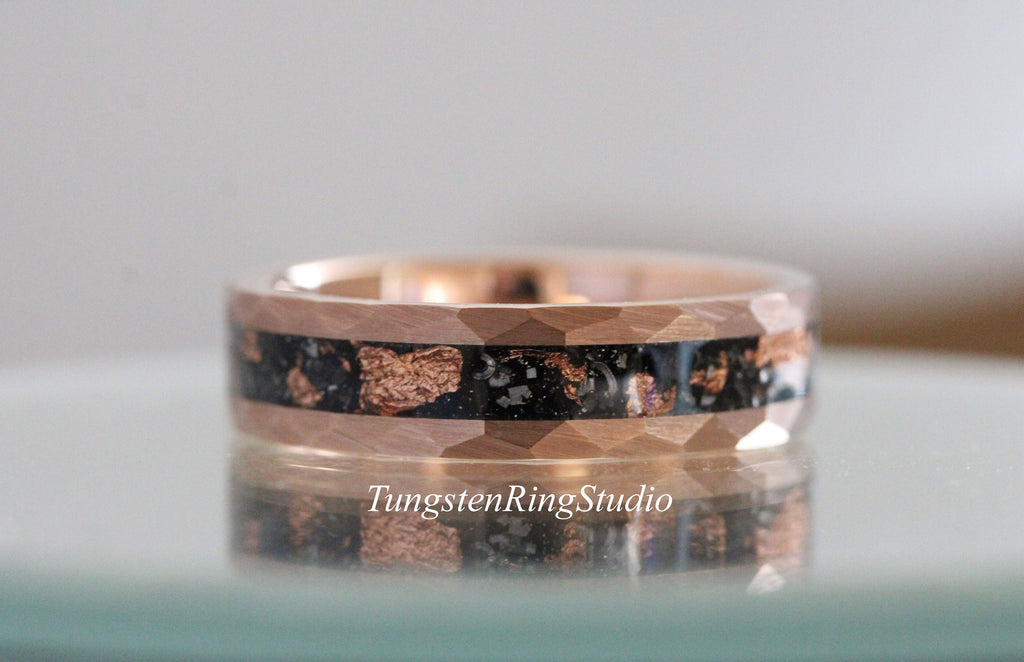 May include: A rose gold tungsten carbide ring with a black inlay and copper flakes. The ring has a hammered finish.