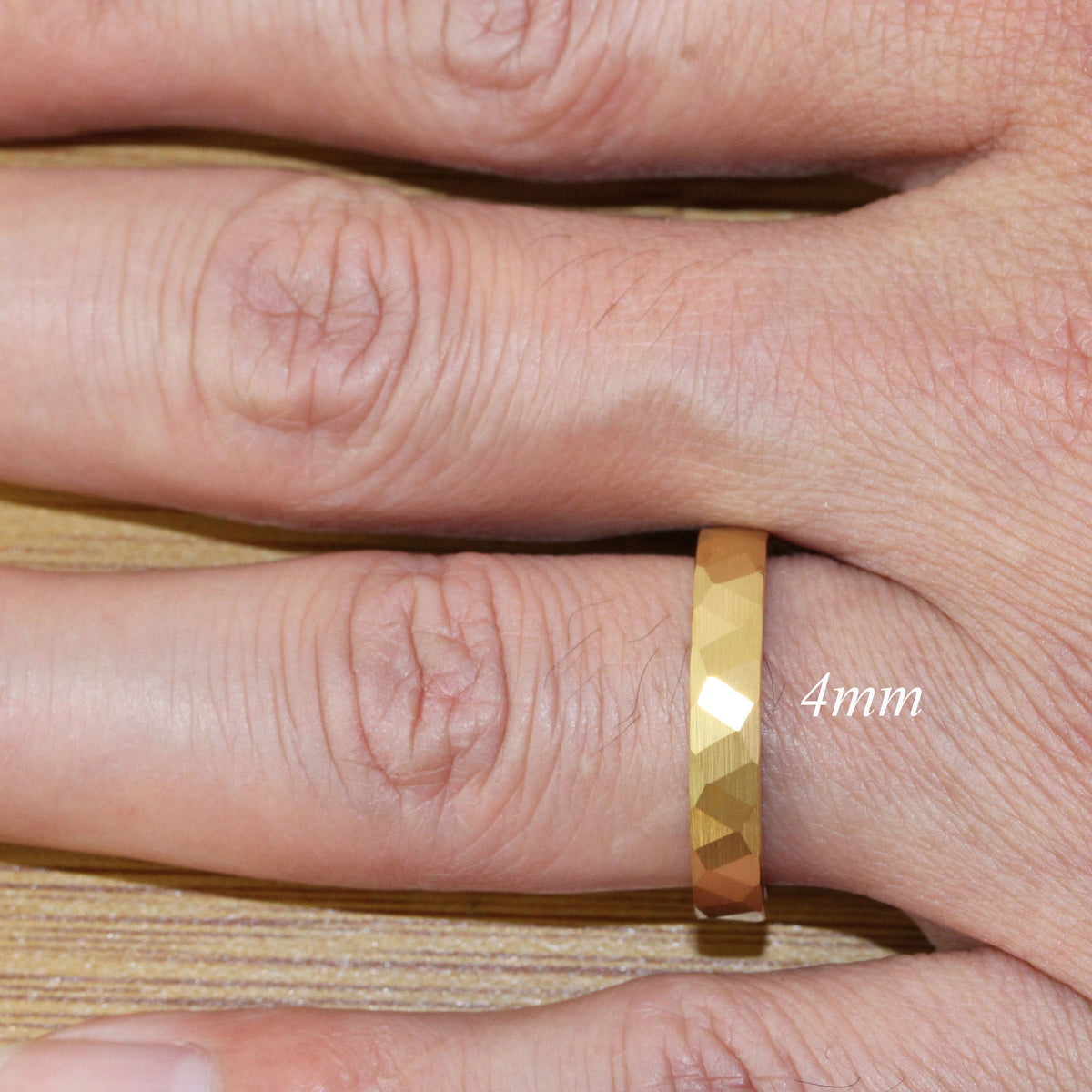 May include: A gold-colored ring with a textured, faceted design. The ring is 4mm wide.