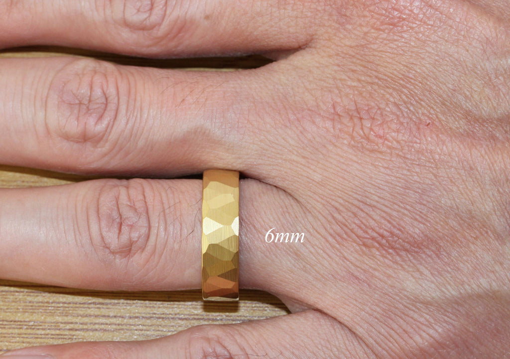 May include: A gold-colored ring with a hammered texture. The ring is 6mm wide and is worn on a person's finger.