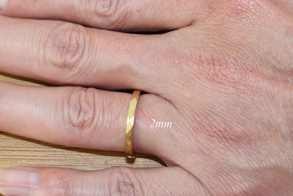 May include: A gold band ring with a faceted design. The ring is 2mm wide.