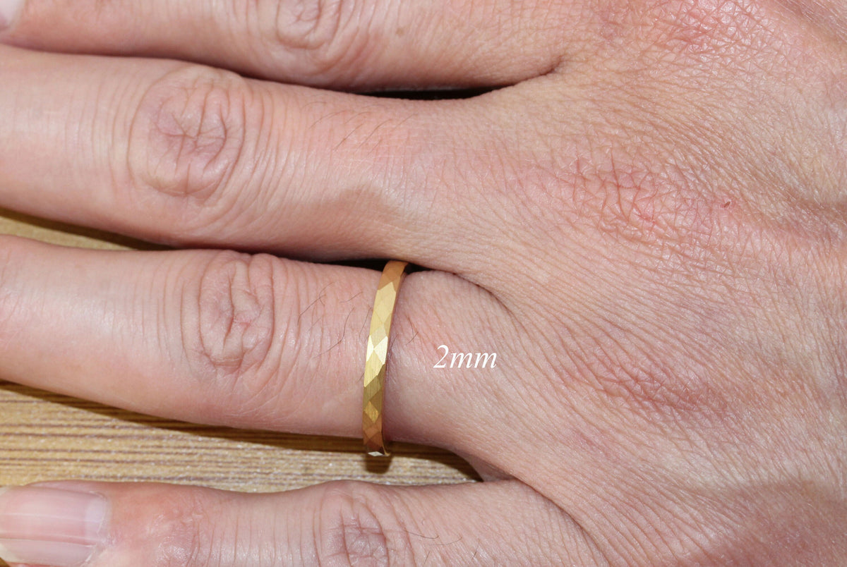 May include: A gold band ring with a faceted design. The ring is 2mm wide.