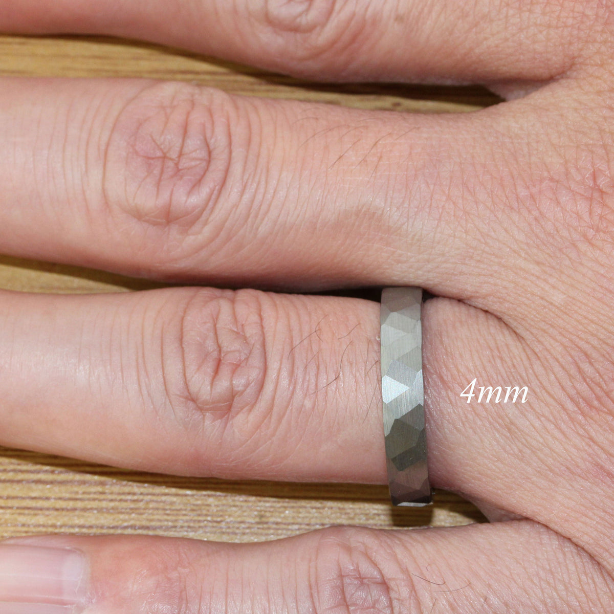 May include: A silver-toned ring with a textured, faceted design. The ring is 4mm wide.