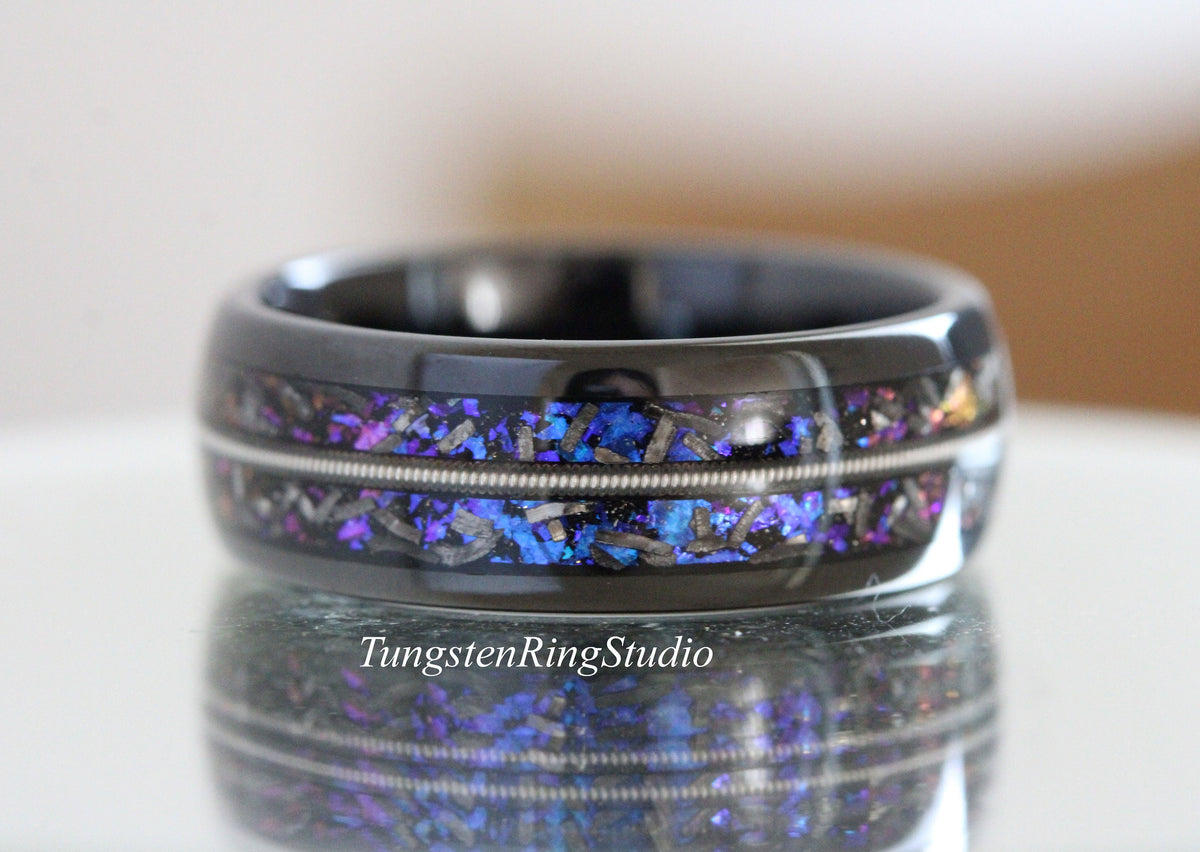 May include: Black tungsten carbide ring with a blue and purple iridescent inlay and two silver bands. TungstenRingStudio is printed on the bottom of the image.