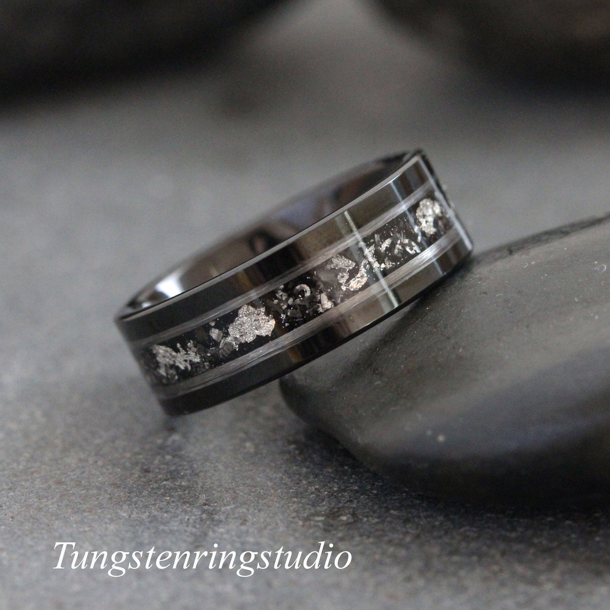 May include: A black tungsten carbide ring with a silver inlay. The inlay has a scattered pattern of small silver pieces.