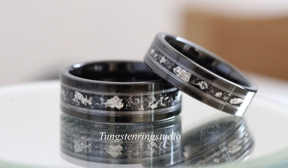 May include: Two black tungsten carbide rings with silver inlay. The rings have a beveled edge and a polished finish.