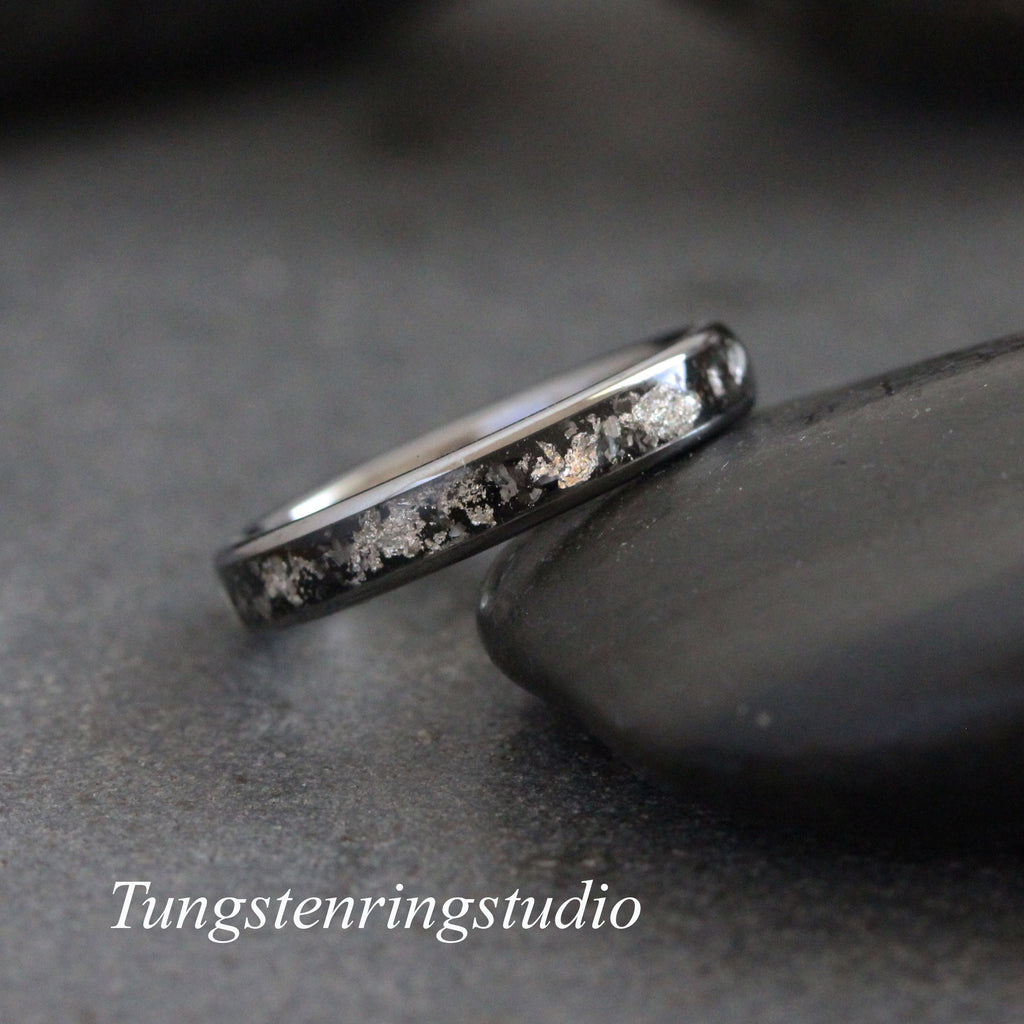 May include: A black tungsten carbide ring with a silver inlay. The ring is on a gray background.