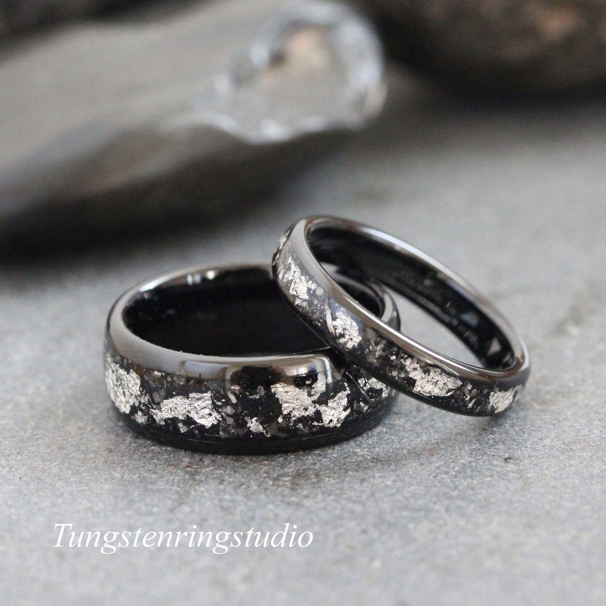 May include: Two black tungsten carbide wedding bands with silver flakes embedded in the black finish.