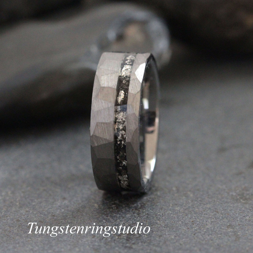 May include: A gray tungsten carbide ring with a hammered finish and a black inlay. The ring has a polished edge and a comfortable fit.