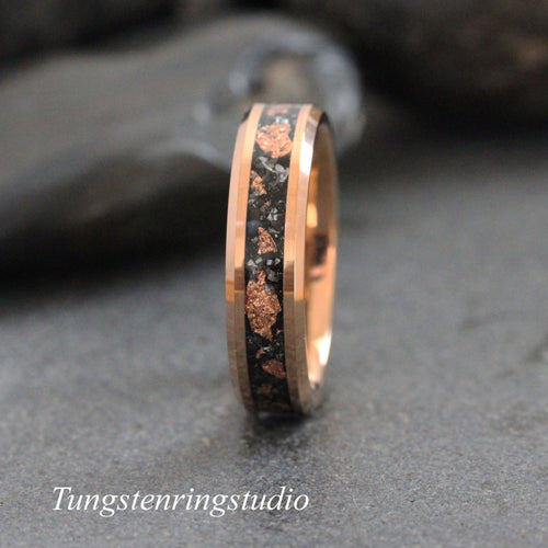 May include: A tungsten carbide ring with a black and rose gold inlay. The inlay features a pattern of small, irregular shapes.